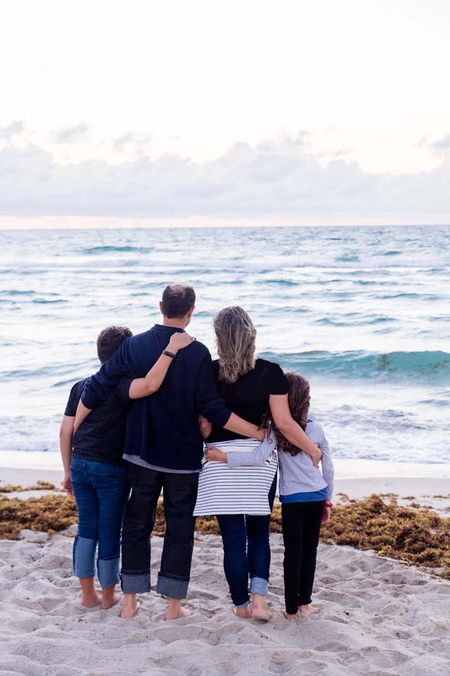 משפחה עומדת עם הגב למצלמה ליד הים